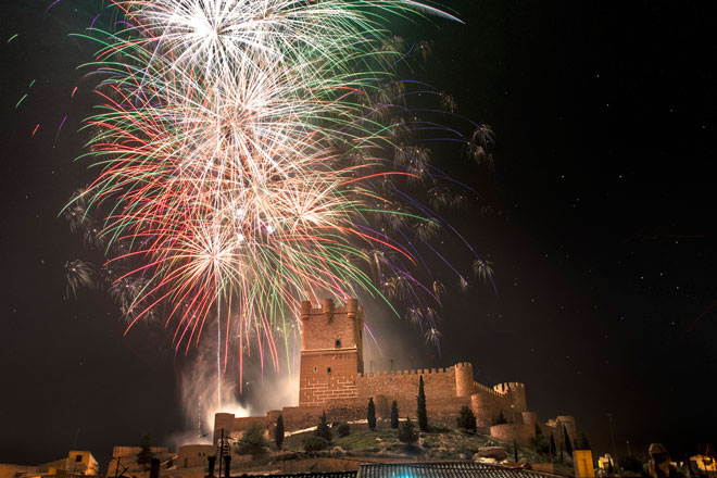 Imagen nocturna del Castillo de la Atalaya junto a fuegos artificiales